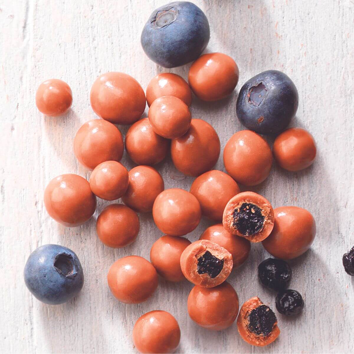 ROYCE' Chocolate - Blueberry Chocolate - Image shows blueberries and chocolate-coated berries with white wooden background
