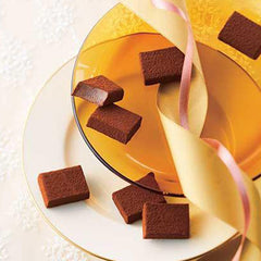 Image shows blocks of chocolate on gold and yellow plates with ribbons in gold and pink.