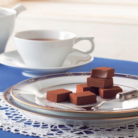 Image shows chocolates on plate with fork. Background has cup on plate.