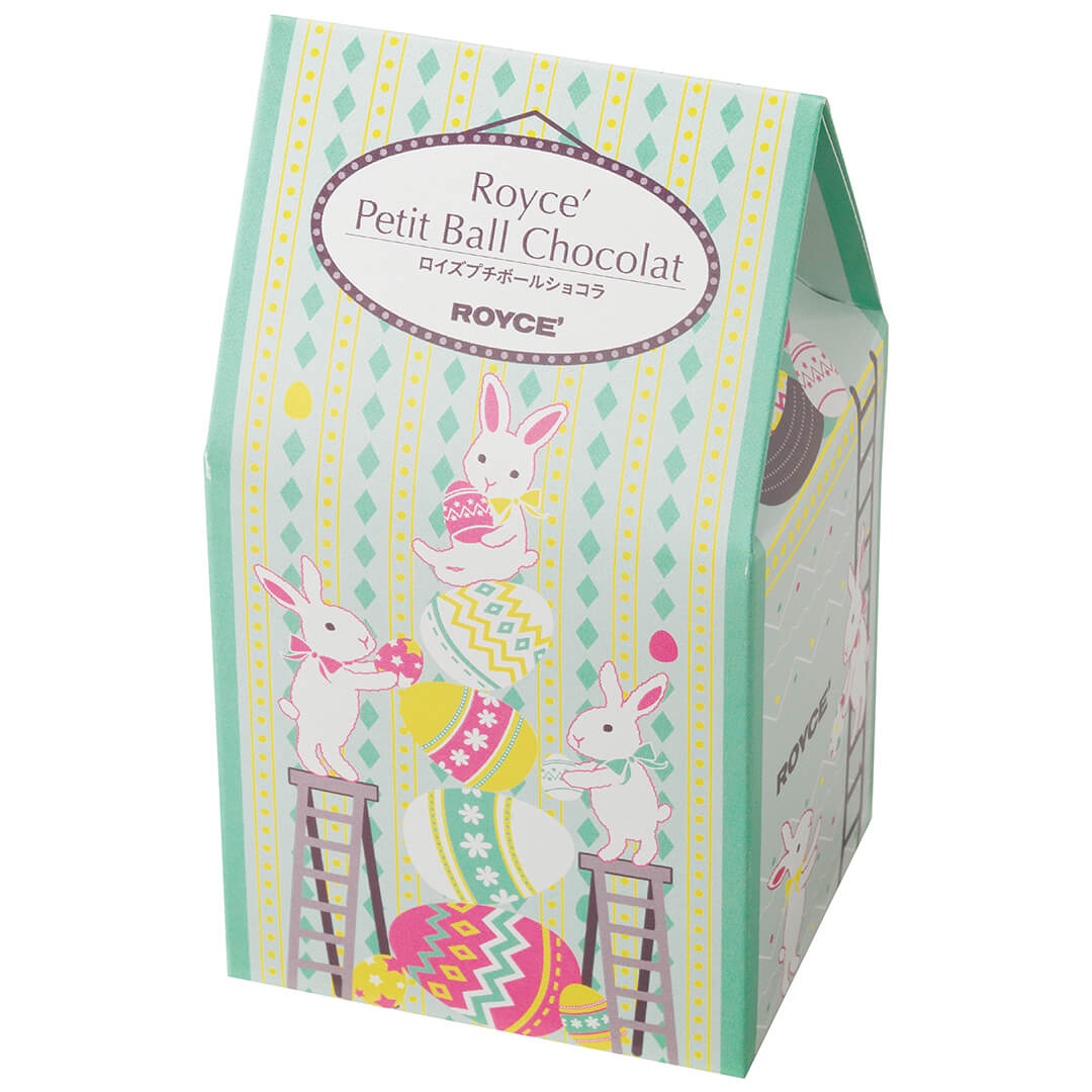 Image shows a printed box with illustrations of eggs, ladders, and rabbits. Text says ROYCE' Petit Ball Chocolat ROYCE'. Background is in white.