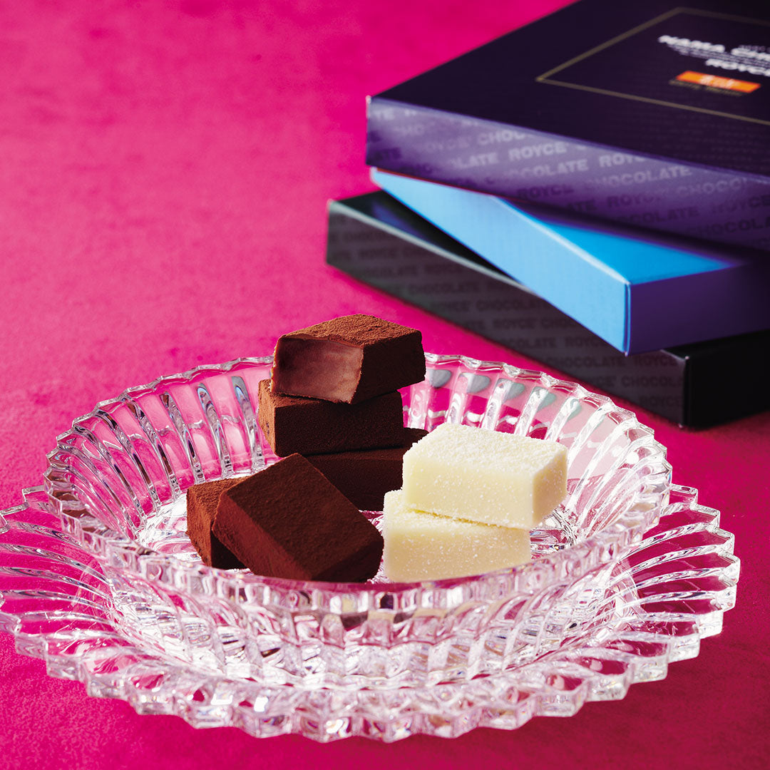 ROYCE' Prestige Nama Chocolate Collection - Image shows chocolate blocks on a clear plate with boxes in the background.